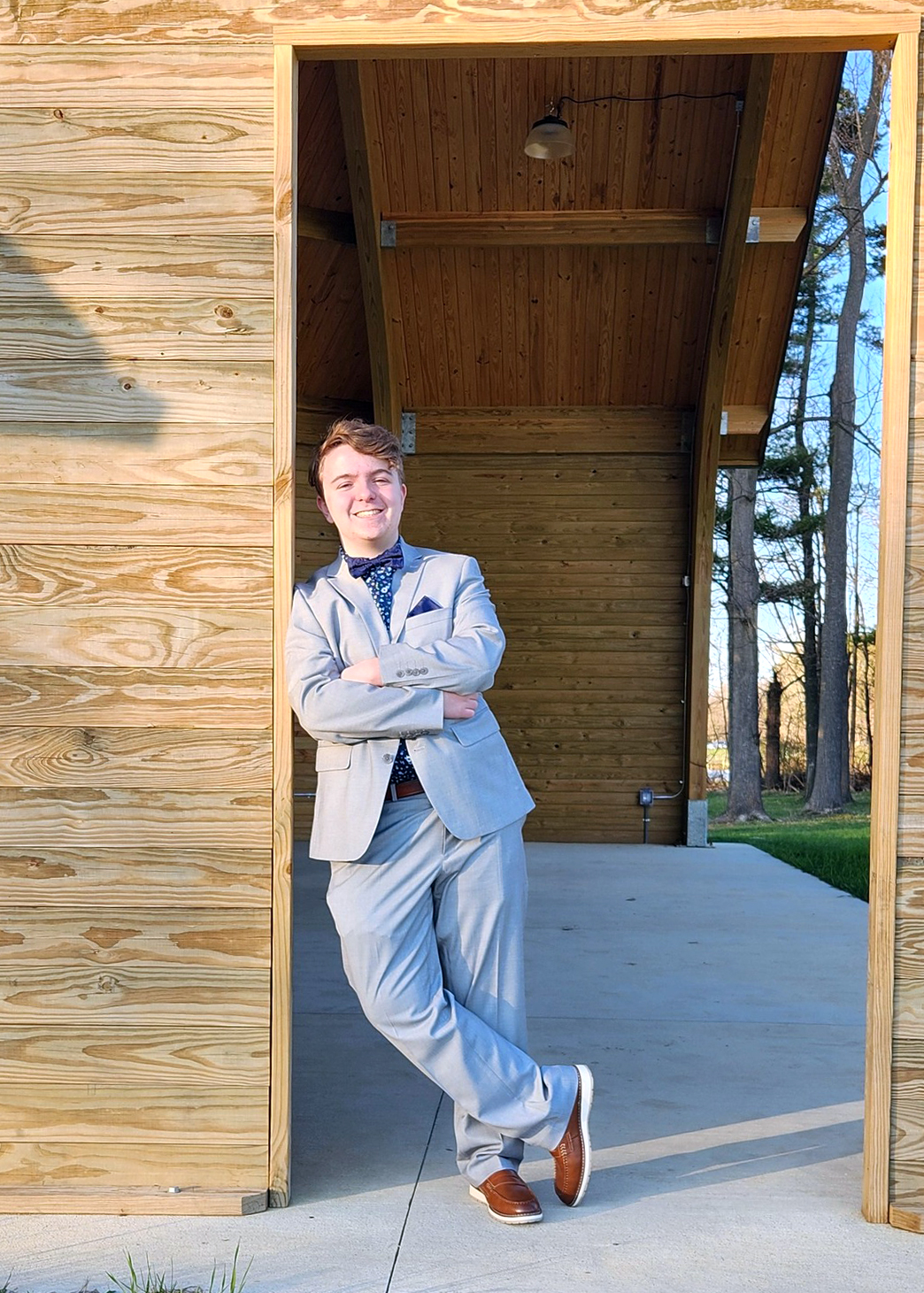 Isaac Bohne standing in a doorway wearing a gray suit, blue shirt, and bow tie.