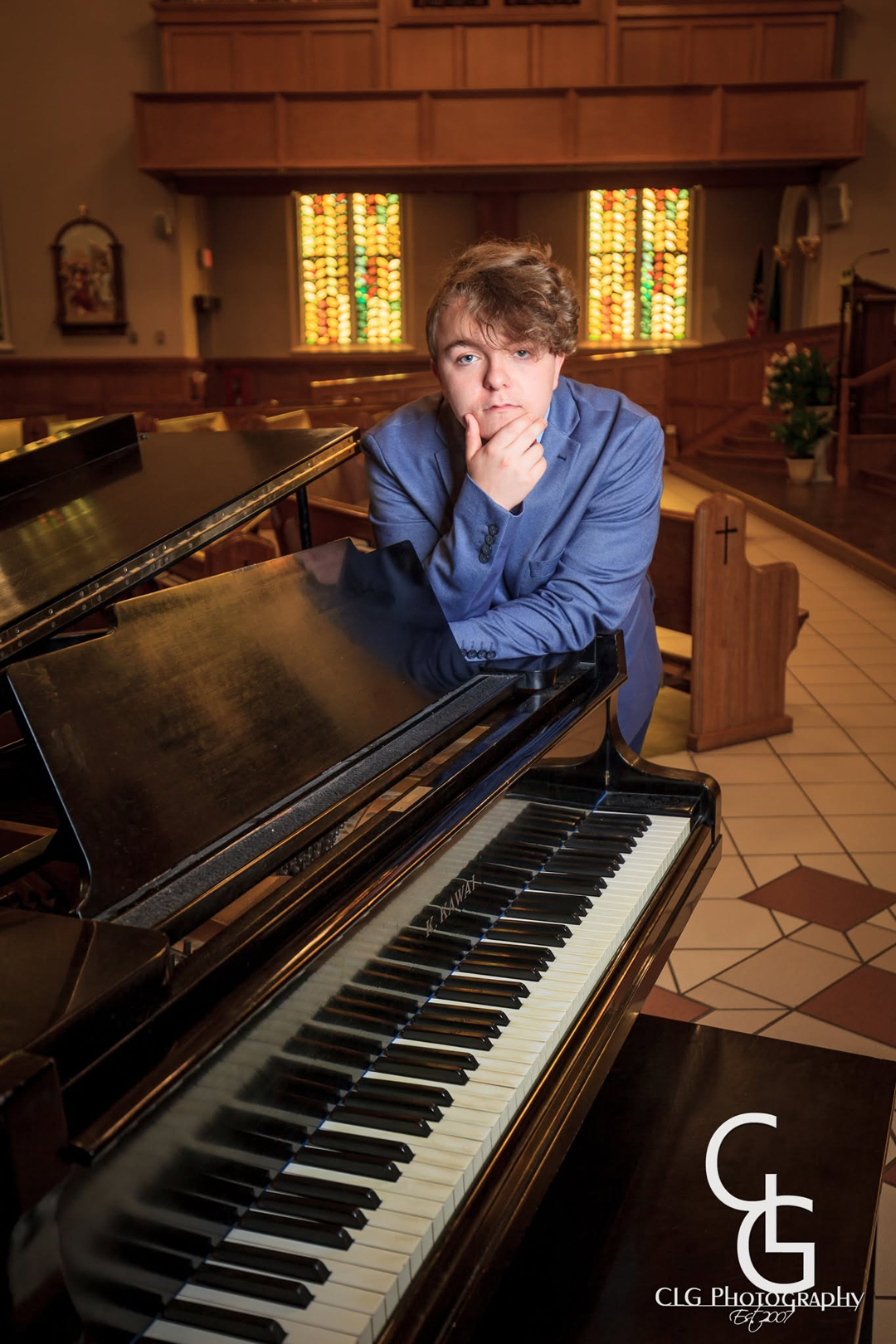 Isaac leaning against a grand piano at St. Mary's church in Norwalk, OH. Photograph by CLG Photography